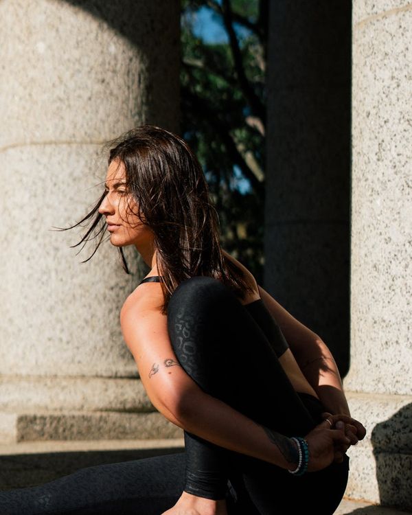 A person sitting in a cross-legged meditation pose by a window.